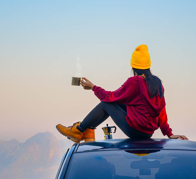 Woman on car drinking tea, View on mountains